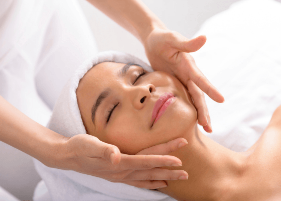 Uma mulher está recebendo uma massagem facial em um spa.