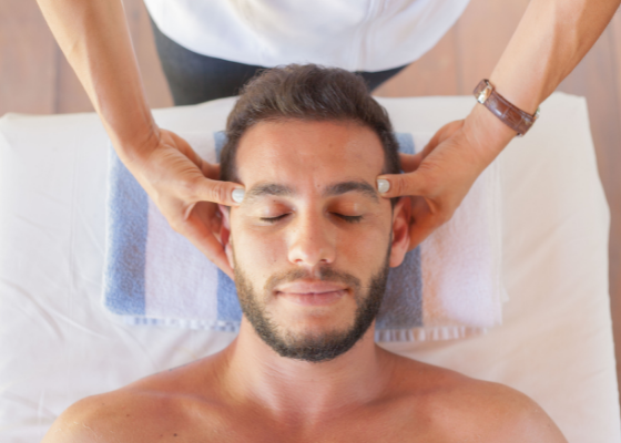 Um homem está recebendo uma massagem na cabeça de uma mulher.