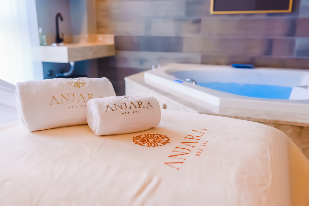 Duas toalhas estão sobre uma mesa de massagem ao lado de uma banheira de hidromassagem.