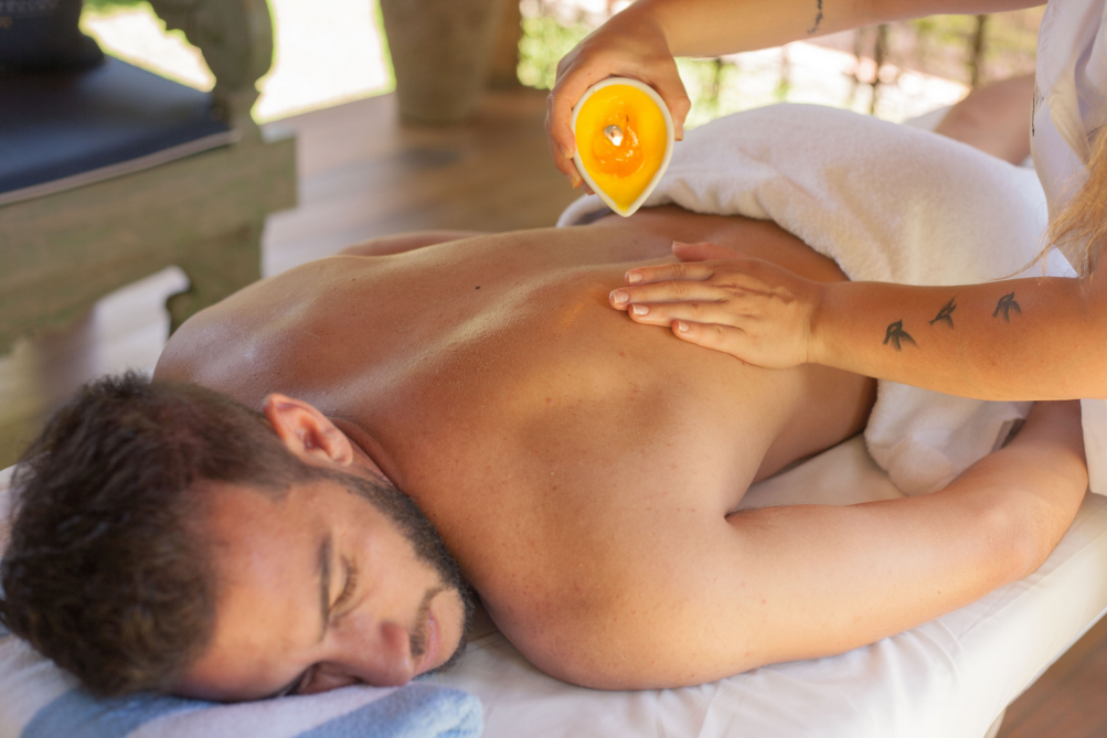 Um homem está recebendo uma massagem com uma vela nas costas.