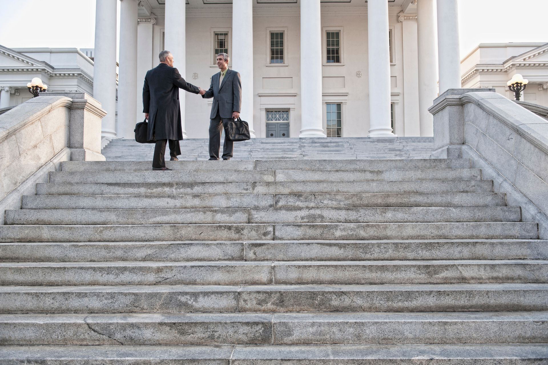 Two men shaking hands on the steps of a building