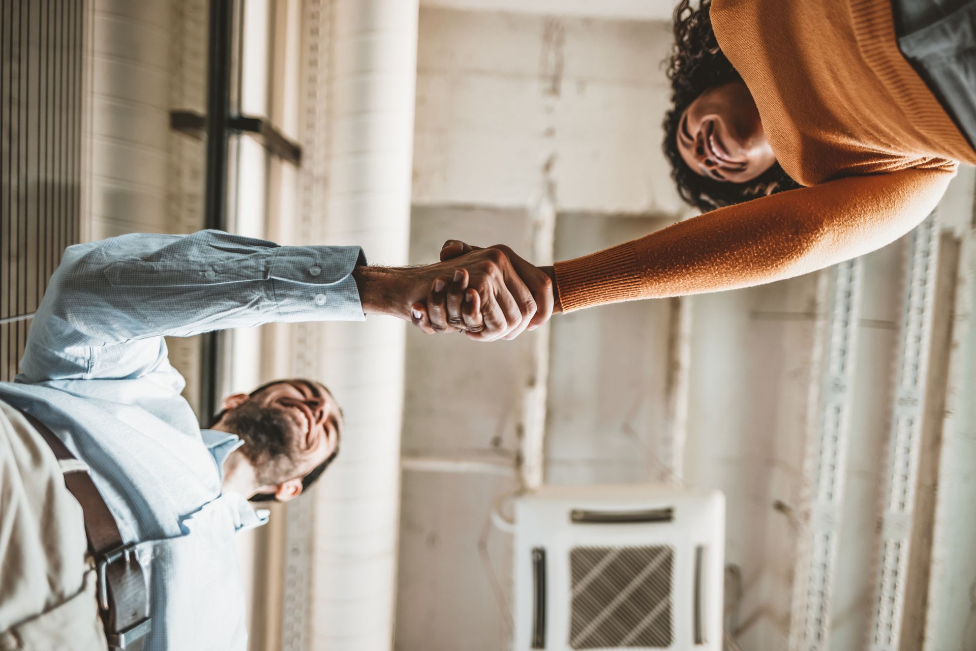 A man and a woman are shaking hands in a room.