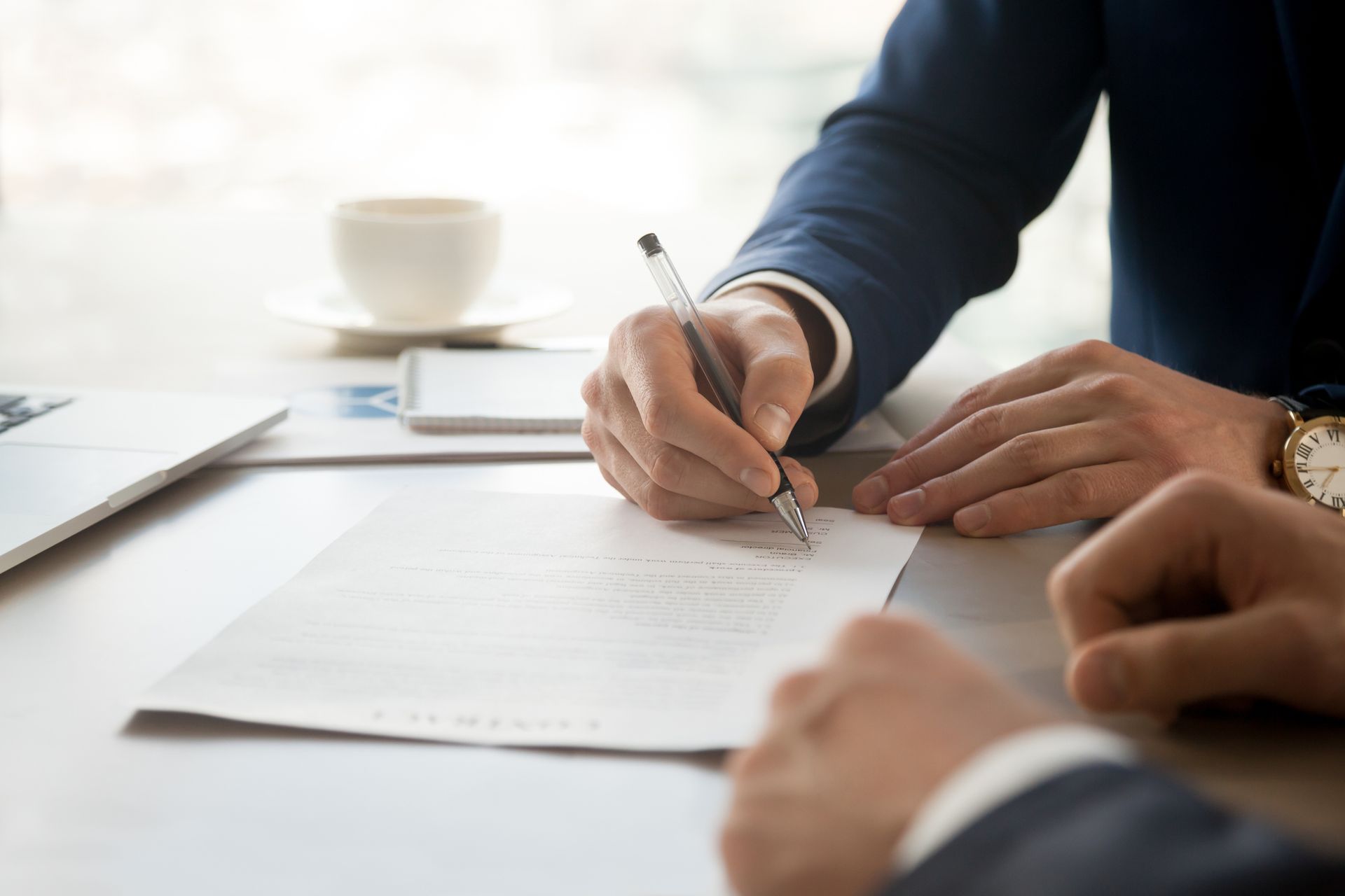 A man is writing on a piece of paper with a pen.