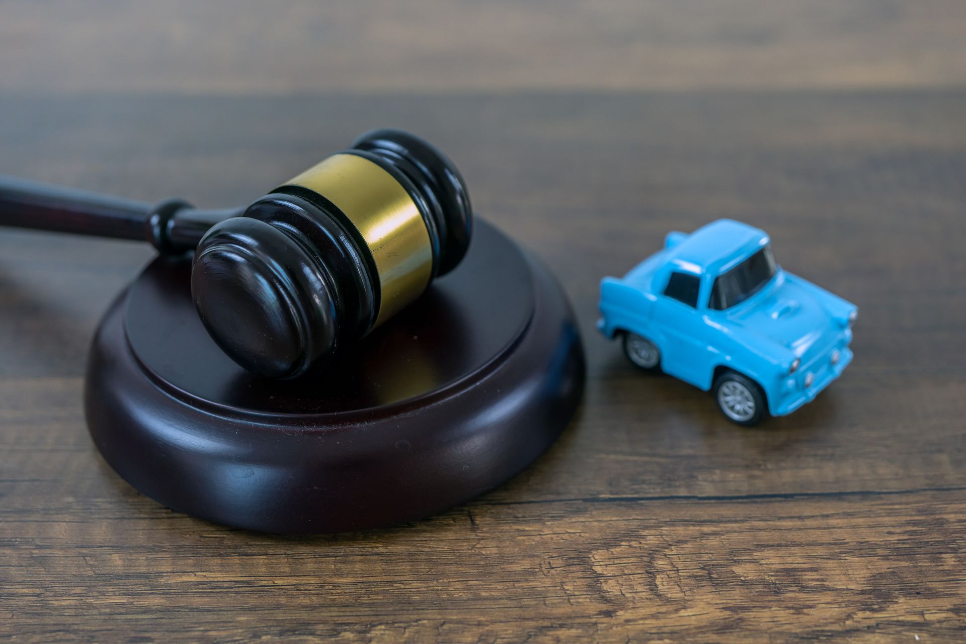 Two toy cars & a judge’s gavel on a wooden table illustrate the concept of auto accident attorney.