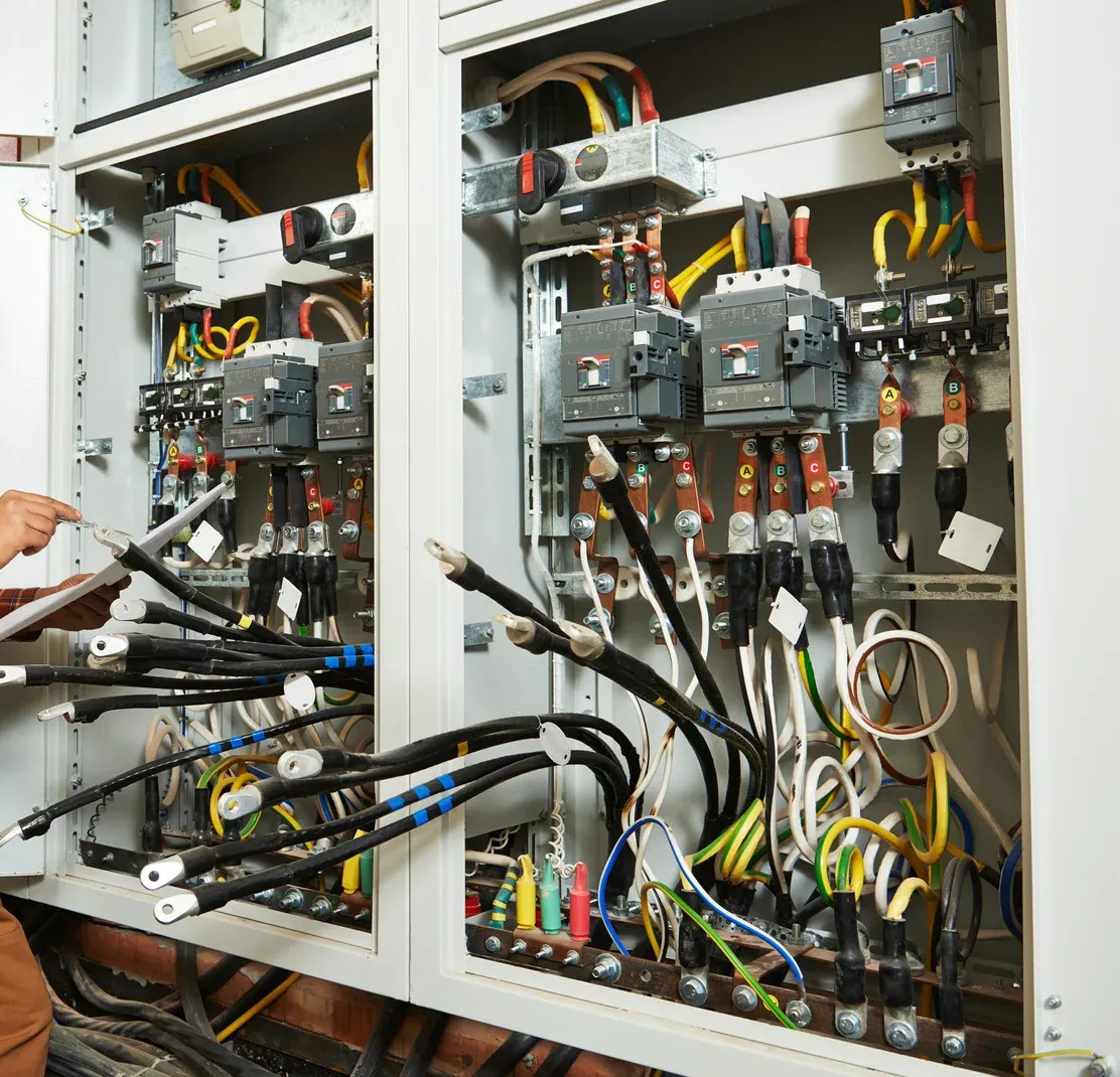 Electrical panel with wires and circuits; person checking the system.