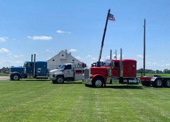 Three semi trucks are parked in a grassy field.