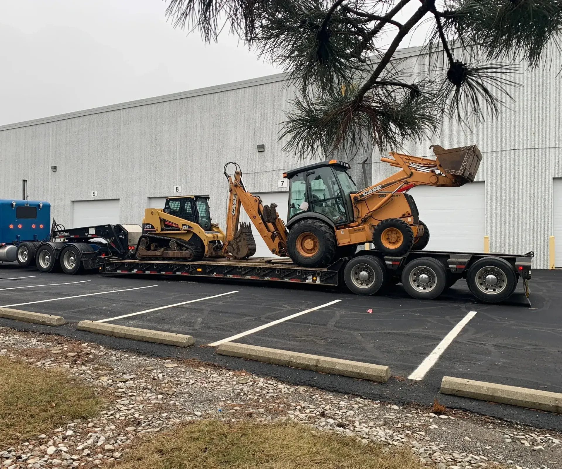 A truck is carrying a bulldozer and a backhoe on a trailer.