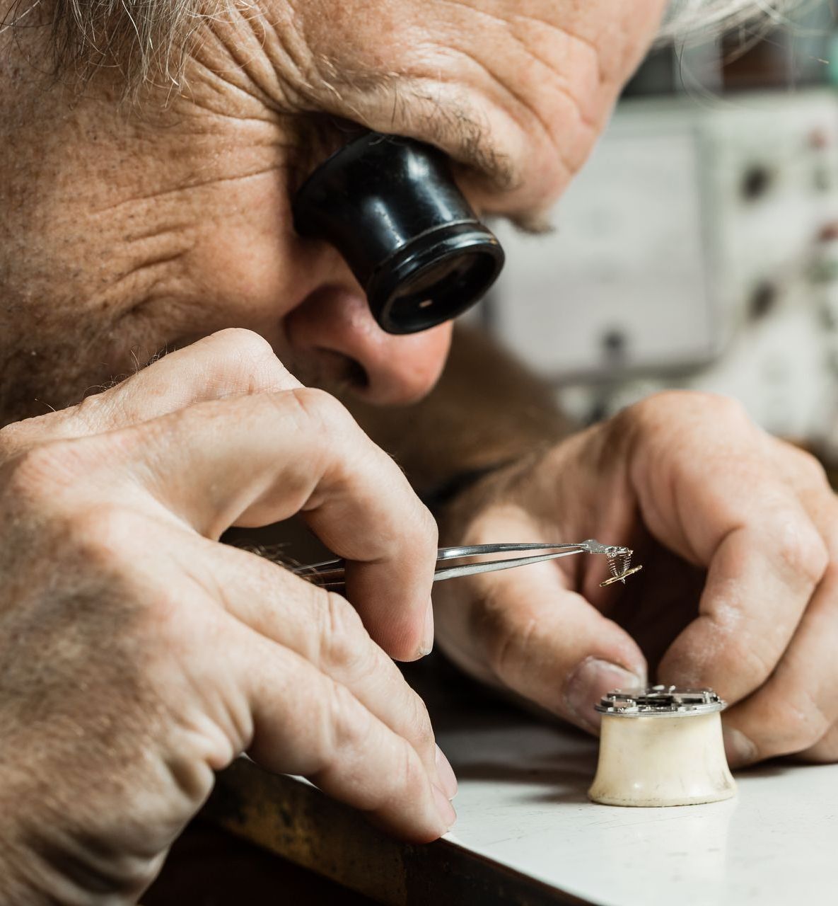 Jeweler using a loupe to inspect a small gem on a workbench