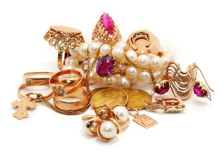 Assorted gold and pearl jewelry, including rings, bracelets, and brooches, arranged on a white background
