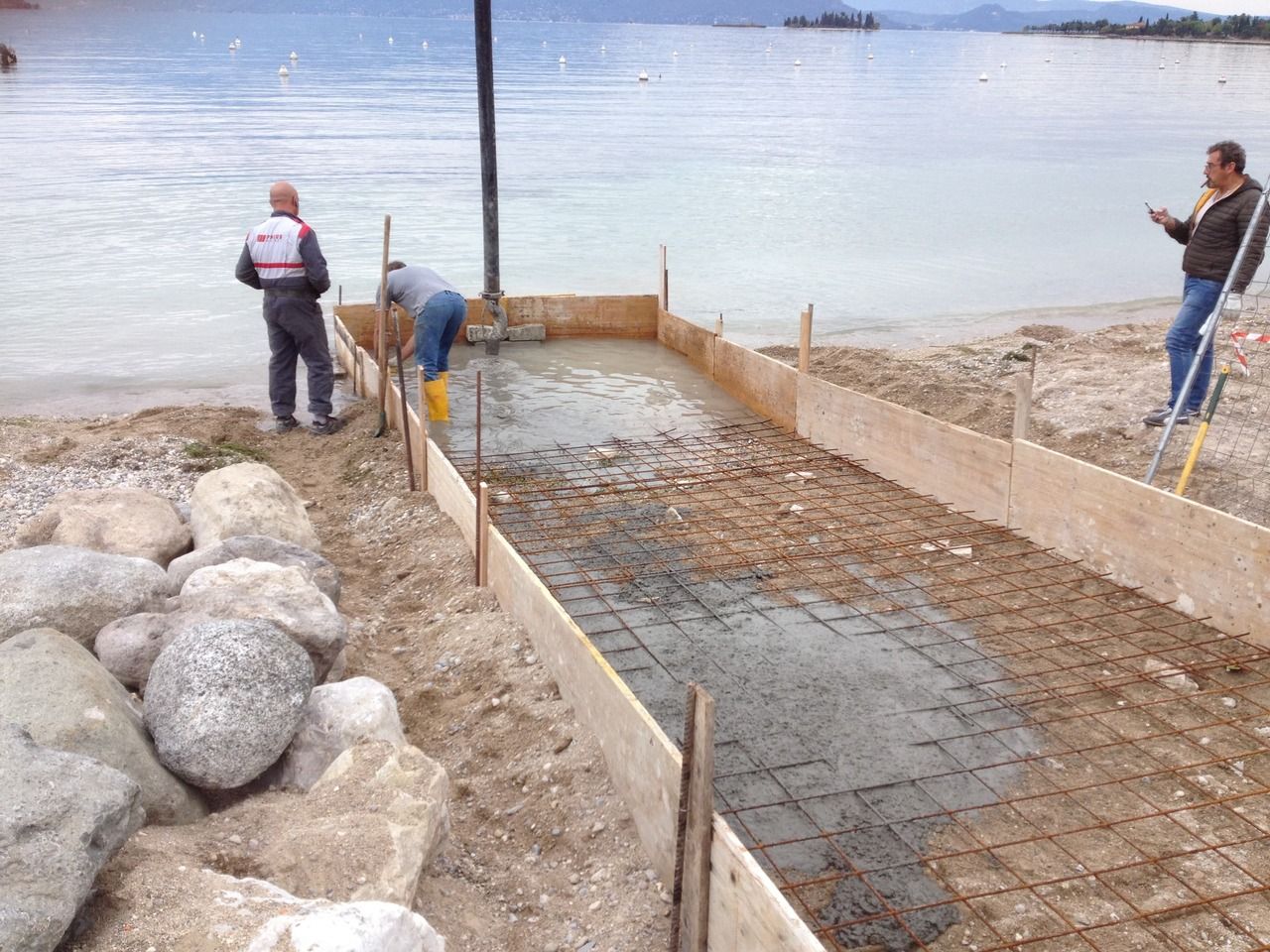 Un gruppo di operai sta lavorando per la realizzazione di uno scivolo su una spiaggia del