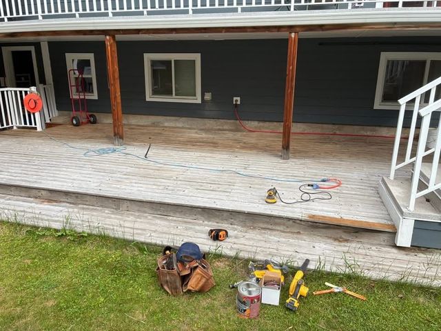 Porch under repair with tools and supplies on the wooden deck beside a house.