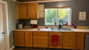 Kitchen with wooden cabinets, window over sink, and red towel hanging from lower cabinet.