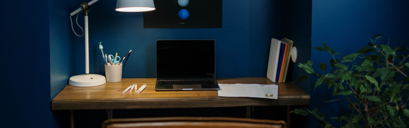 Home office with a lamp, laptop, books and pens