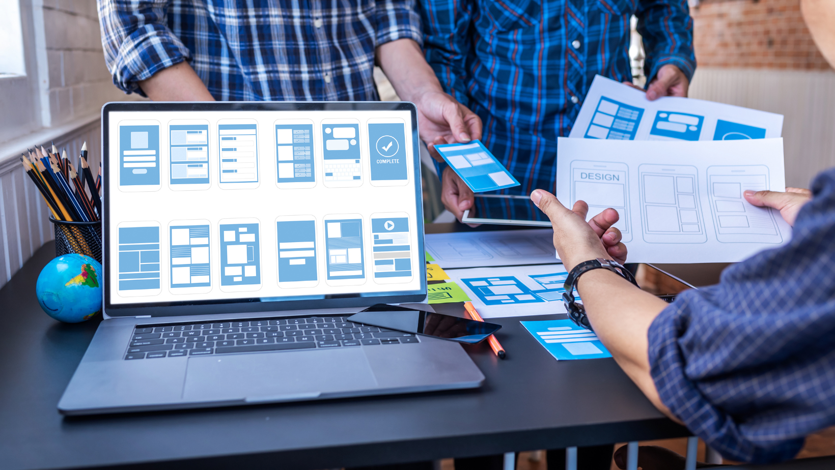 A group of people looking at the user experience design plans on a laptop.
