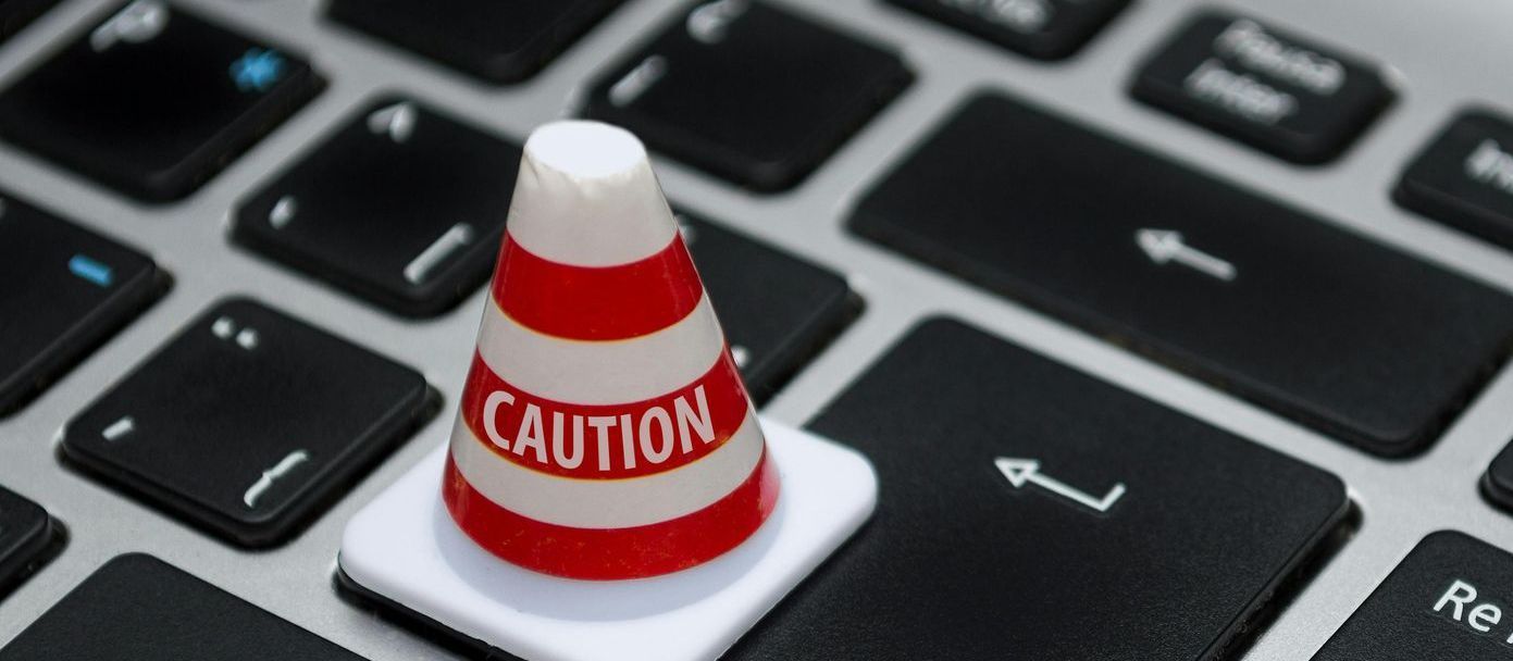 Caution cone in red and white sitting on the Enter key on a keyboard.