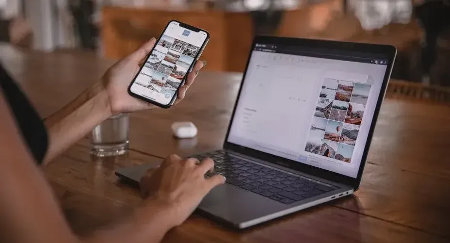 Person looking at phone and computer, looking to post items on social media, almost hesitant.