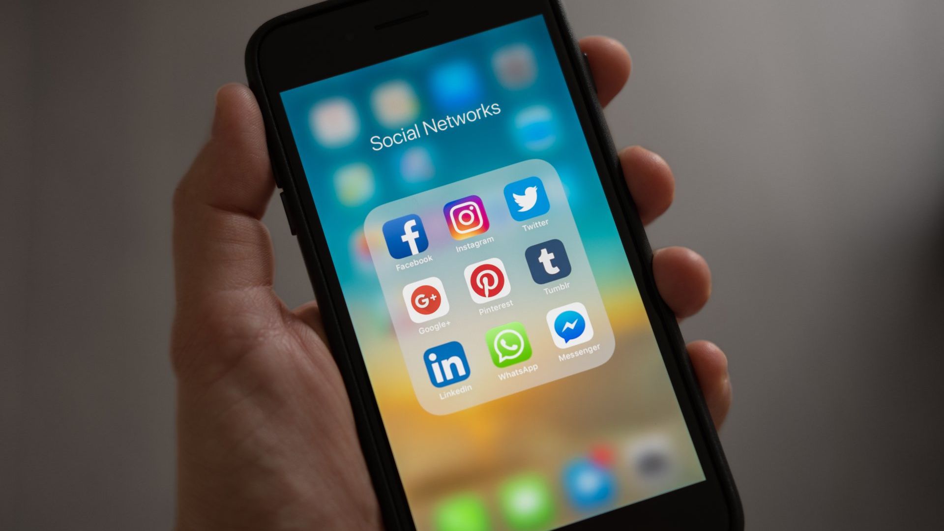 A person is holding a cell phone with social media icons on the screen