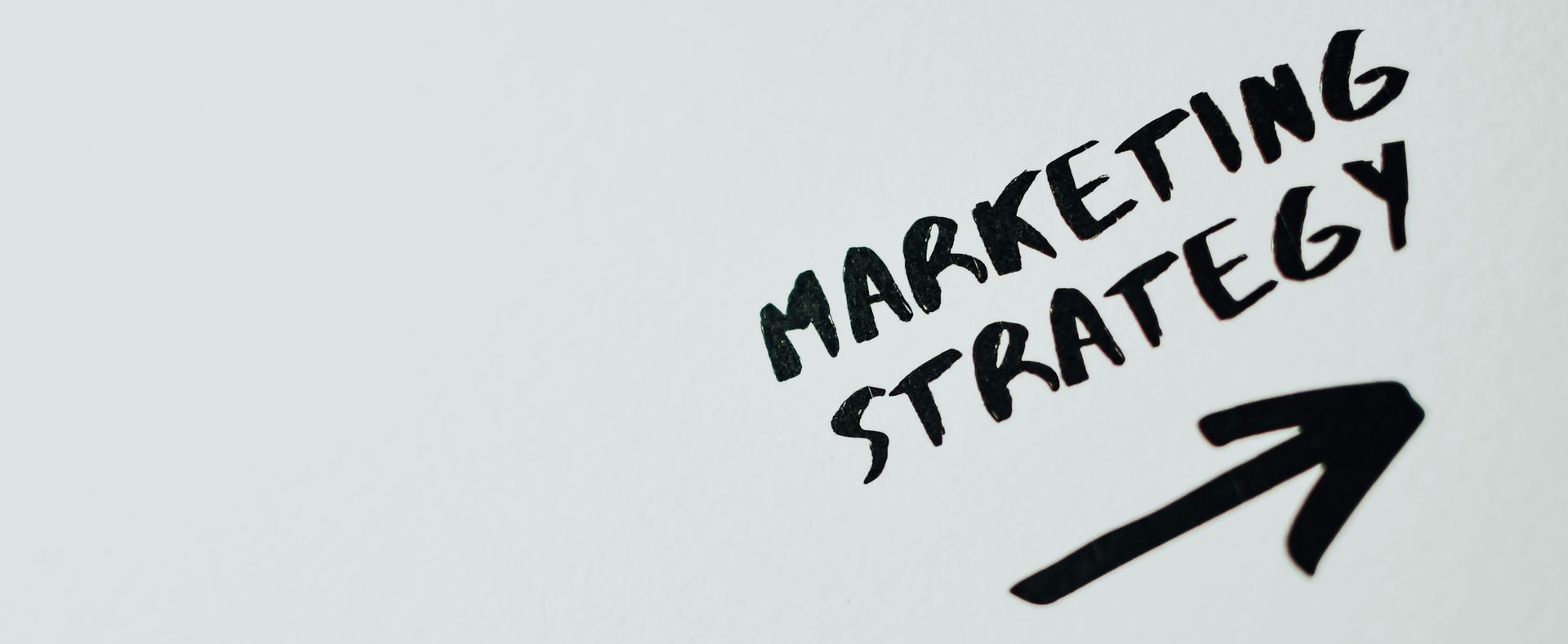 Handwritten words ‘Marketing Strategy’ with an arrow, representing business growth and strategic planning.