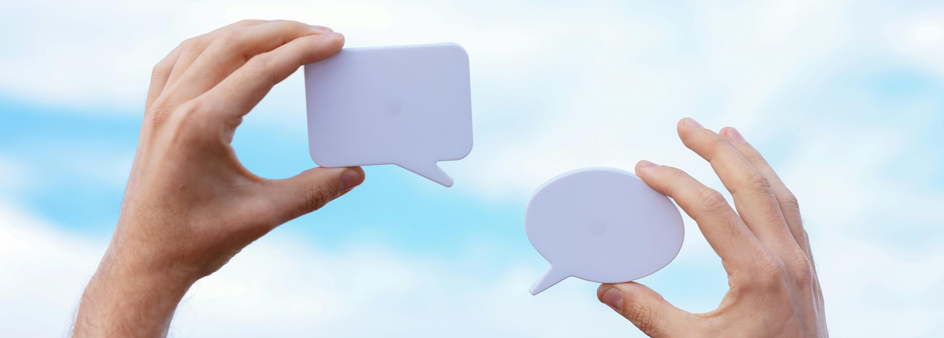Two hands holding chat icons up into the sky.