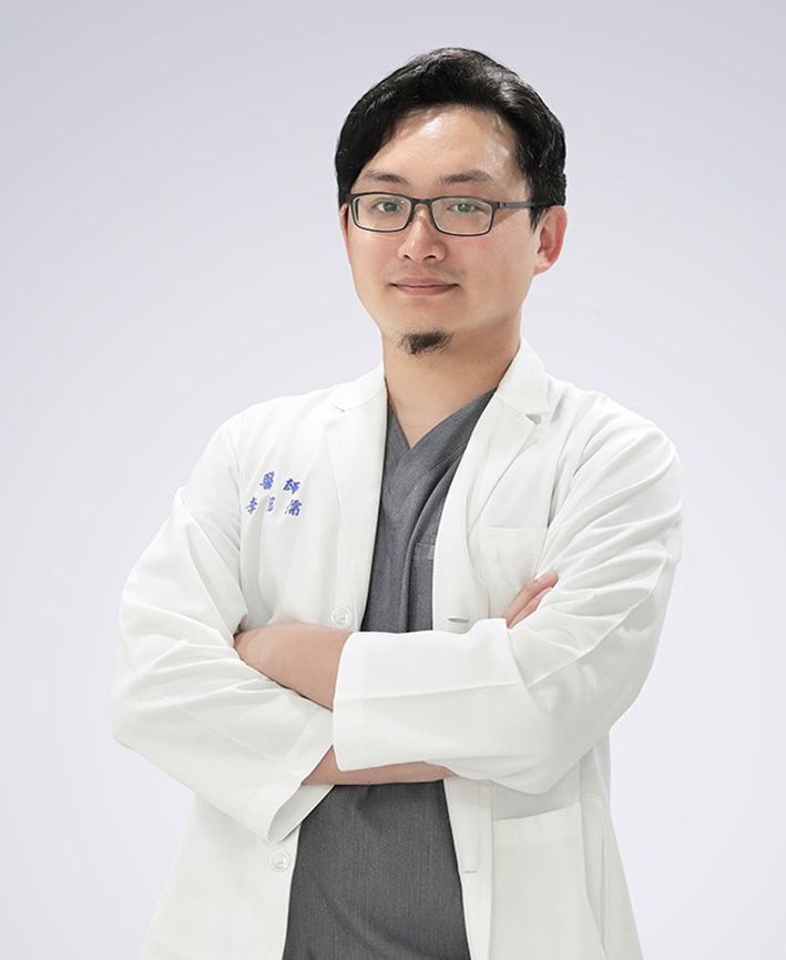A man in a white lab coat and glasses is standing with his arms crossed.