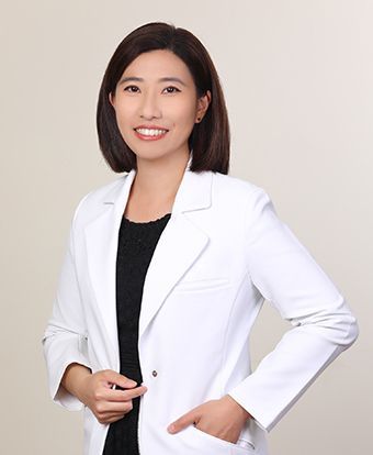 A woman in a white lab coat is smiling for the camera.
