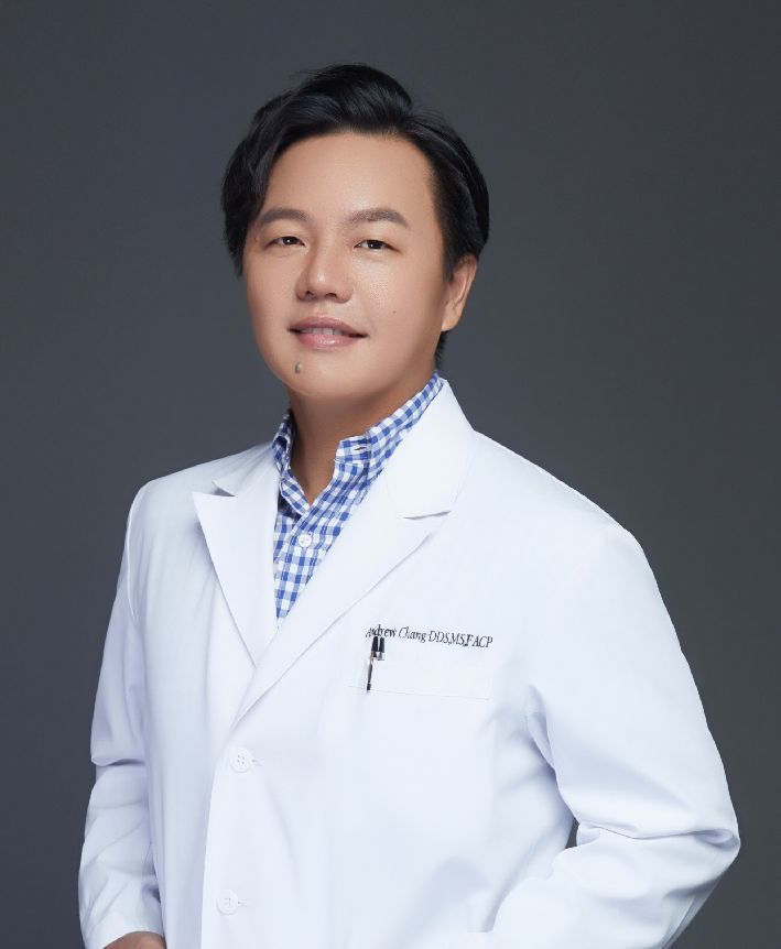 A man in a white lab coat is smiling for the camera