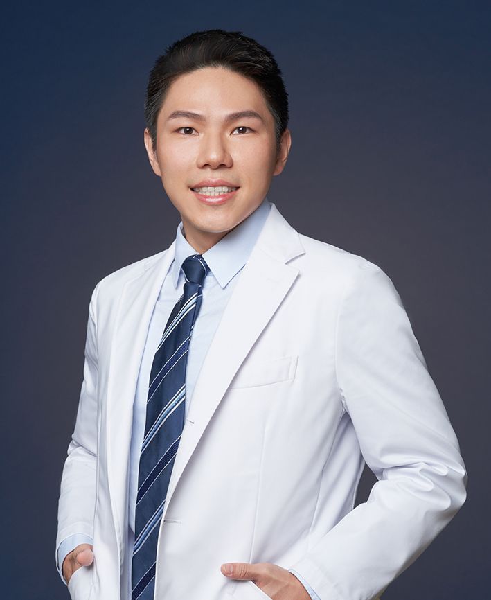 A man in a white coat and tie is smiling for the camera