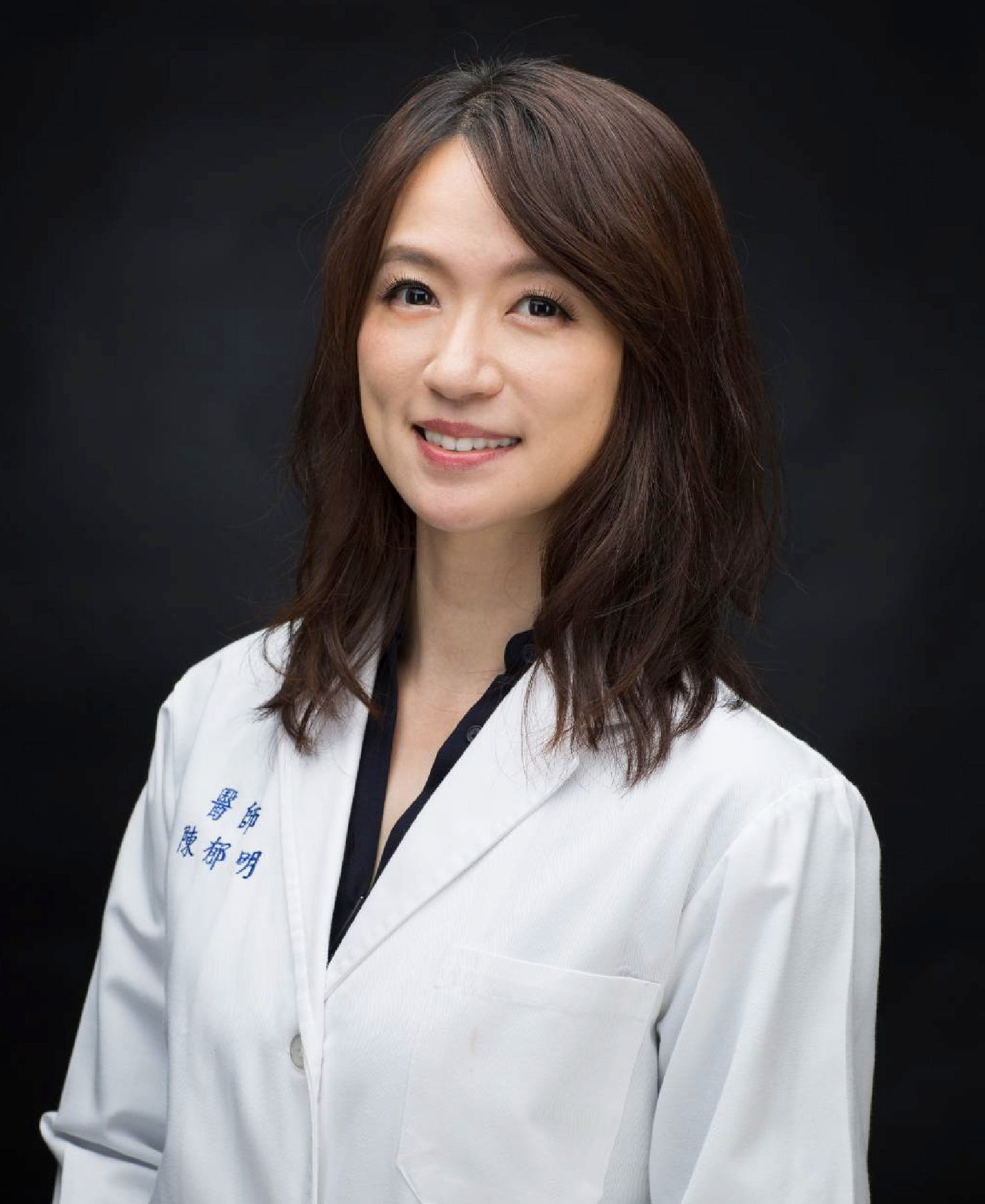 A woman in a white lab coat is smiling for the camera.