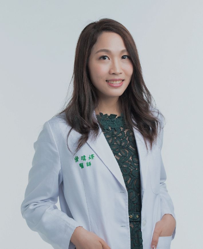 A woman is wearing a white lab coat and a green dress.