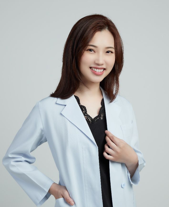 A woman in a lab coat is smiling for the camera.