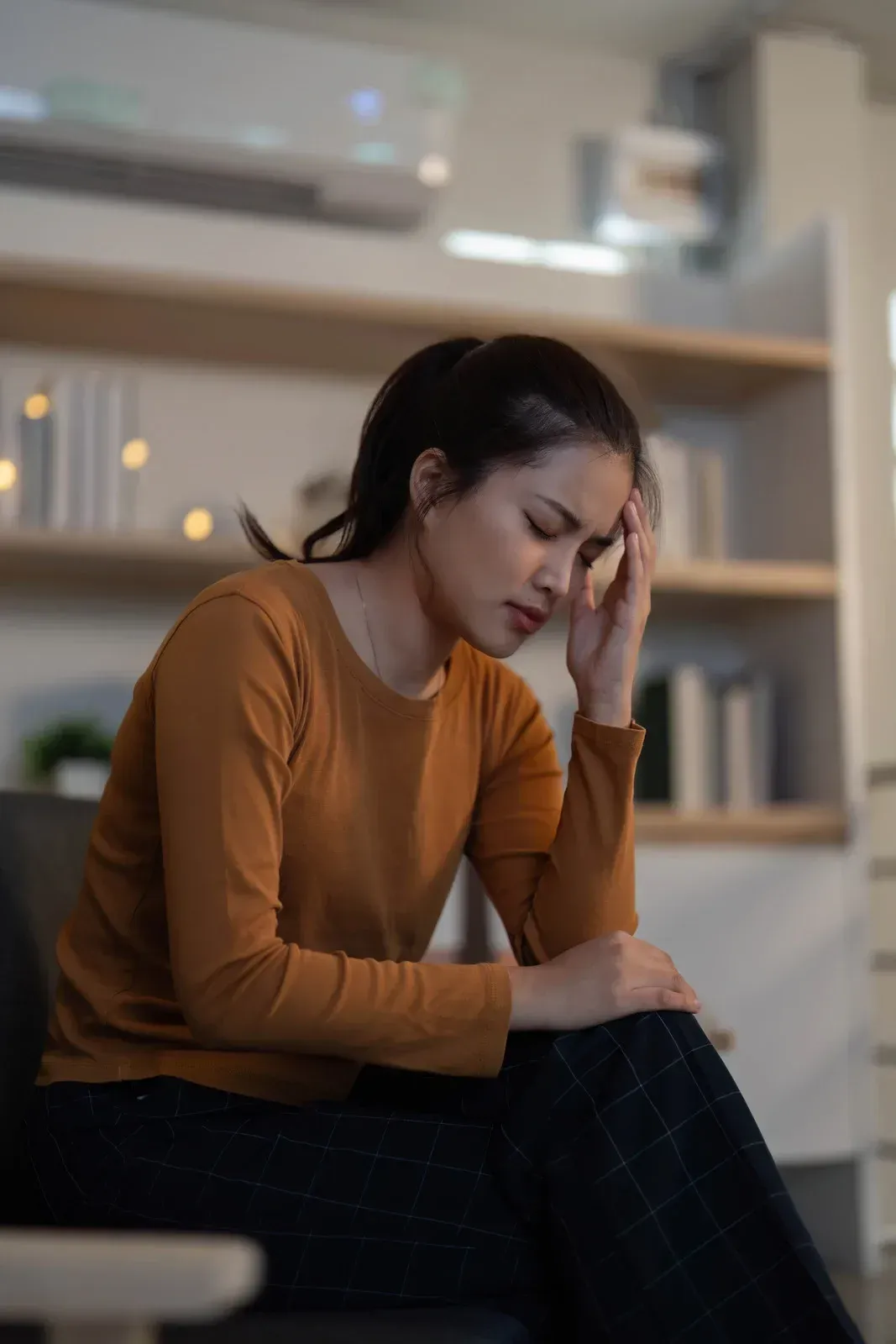 Woman with hands on her face in a library, looking stressed and overwhelmed.