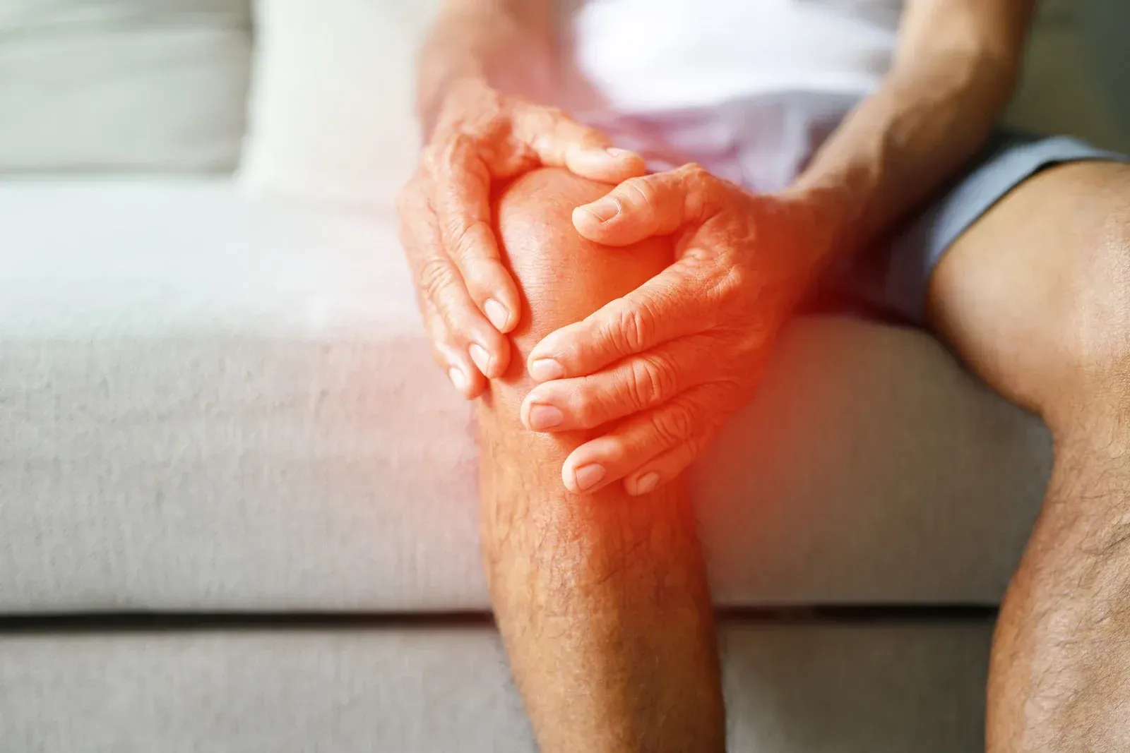 Man holding knee in pain; red highlights indicate pain area.