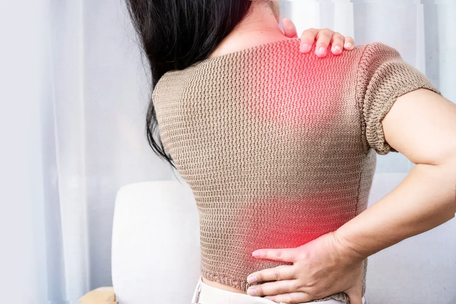 Woman with hand on shoulder, back and lower back, red highlighting pain.