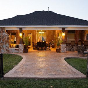 A large brick house with a covered patio and a dining table and chairs.