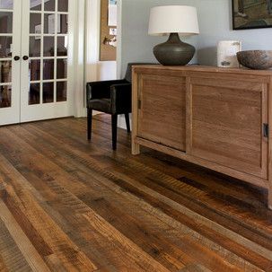 A living room with a wooden floor , a dresser , a chair , and a lamp.