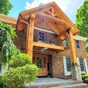 A large brick house with a wooden porch and a wooden roof.