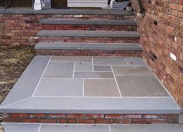 A set of stairs made of stone and brick next to a brick wall.