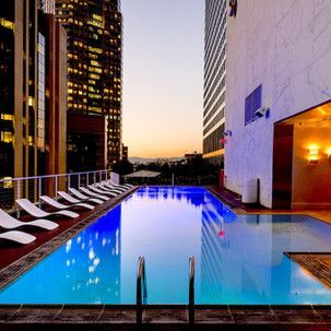 A large swimming pool is surrounded by chairs and buildings at night.