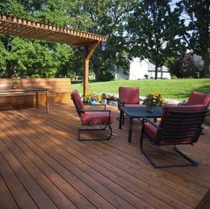 A wooden deck with chairs and a table under a pergola.