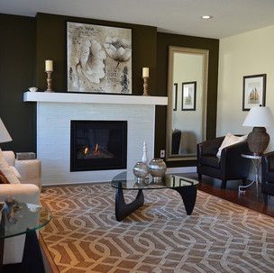 A living room with a fireplace , couch , chair , coffee table and mirror.