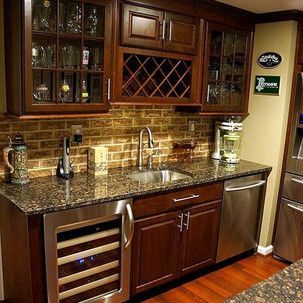 A kitchen with stainless steel appliances , wooden cabinets , granite counter tops and a wine cooler.