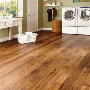 A laundry room with wooden floors , a sink , a washer and dryer , and a basket.