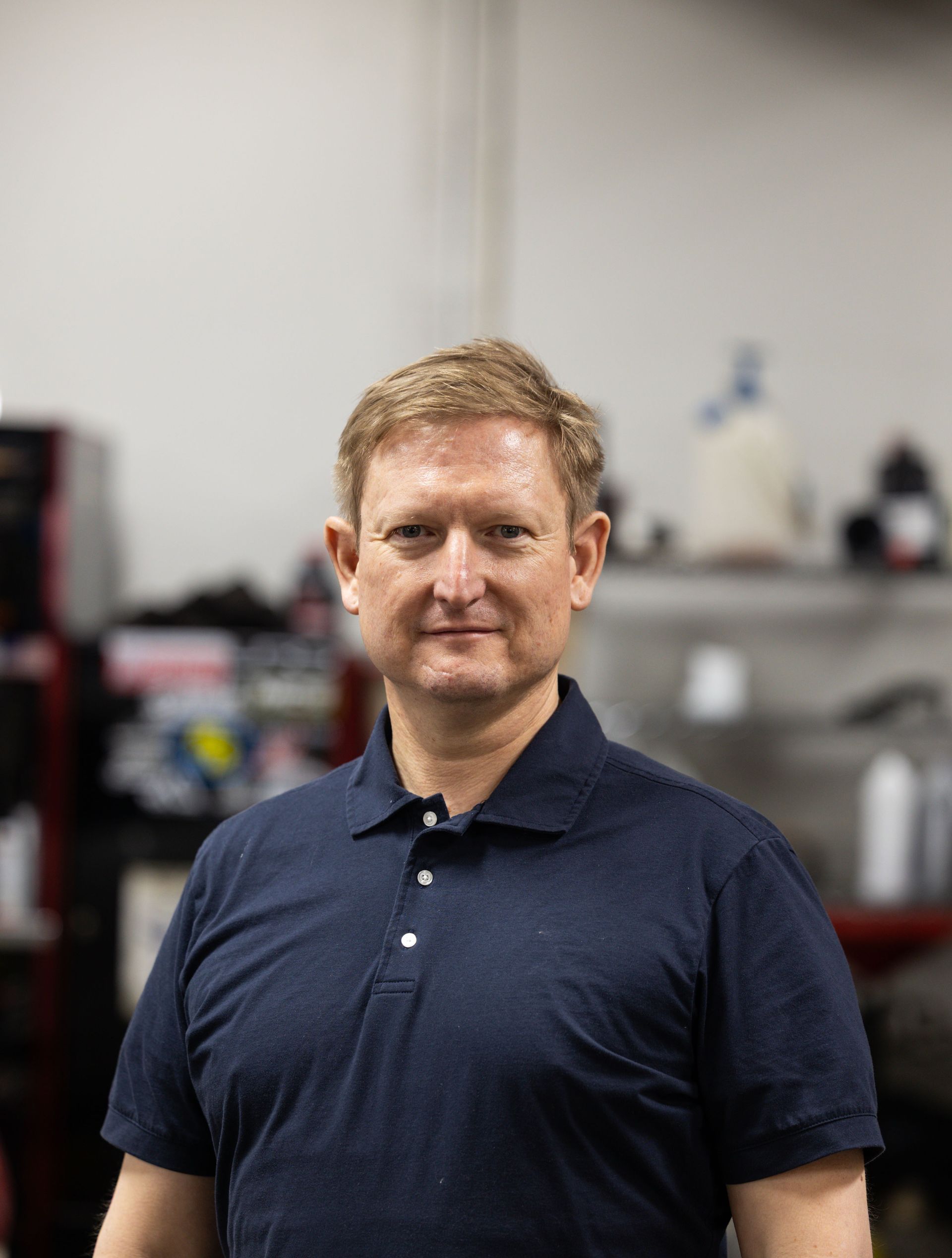 Portrait of a man in a navy polo shirt standing in an office, facing the camera