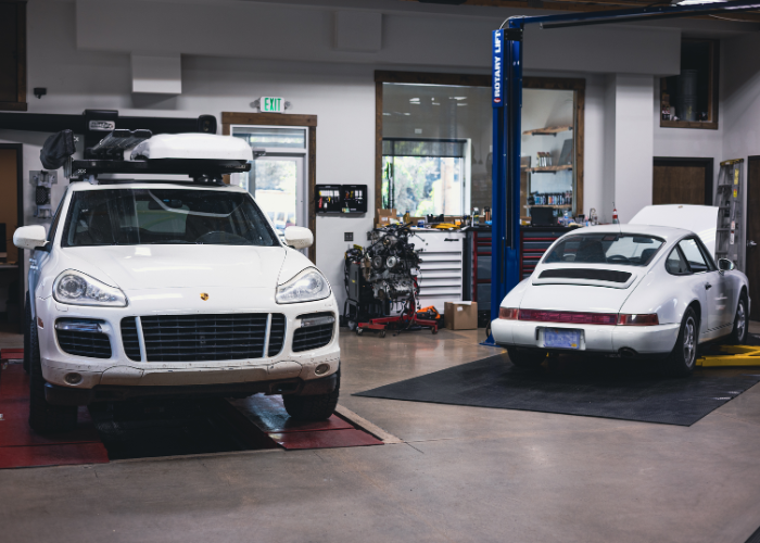 Two modified white SUVs in a garage, one on a lift and one in a service bay.