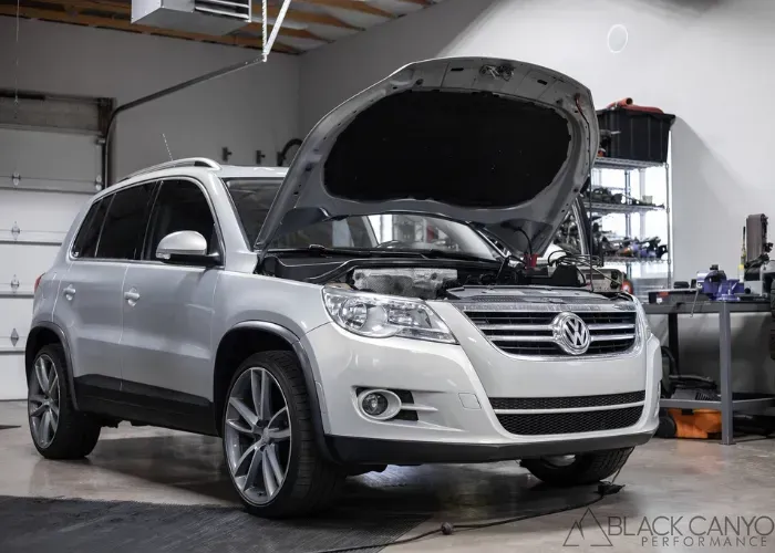 Silver Volkswagen SUV with hood open in an auto repair shop