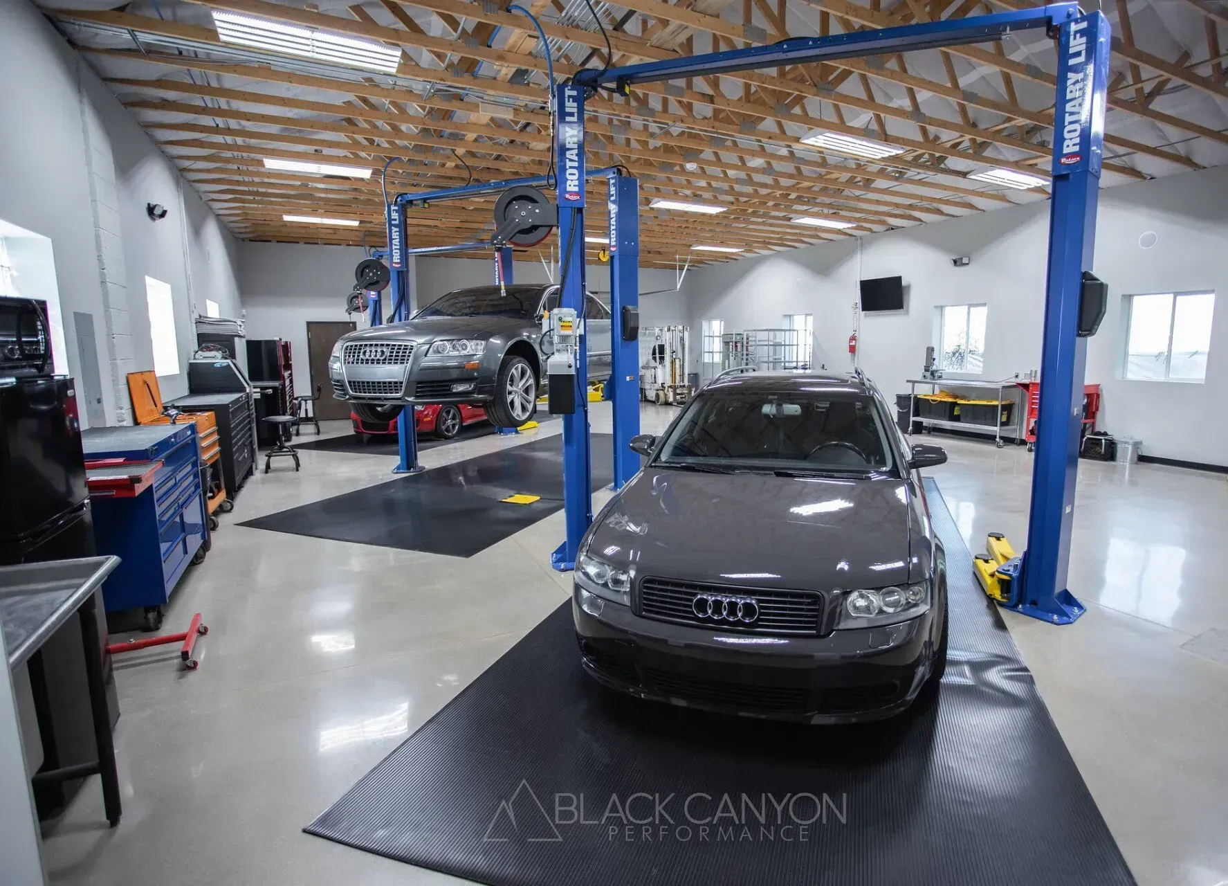 Auto repair shop with two cars on lifts inside a bright garage