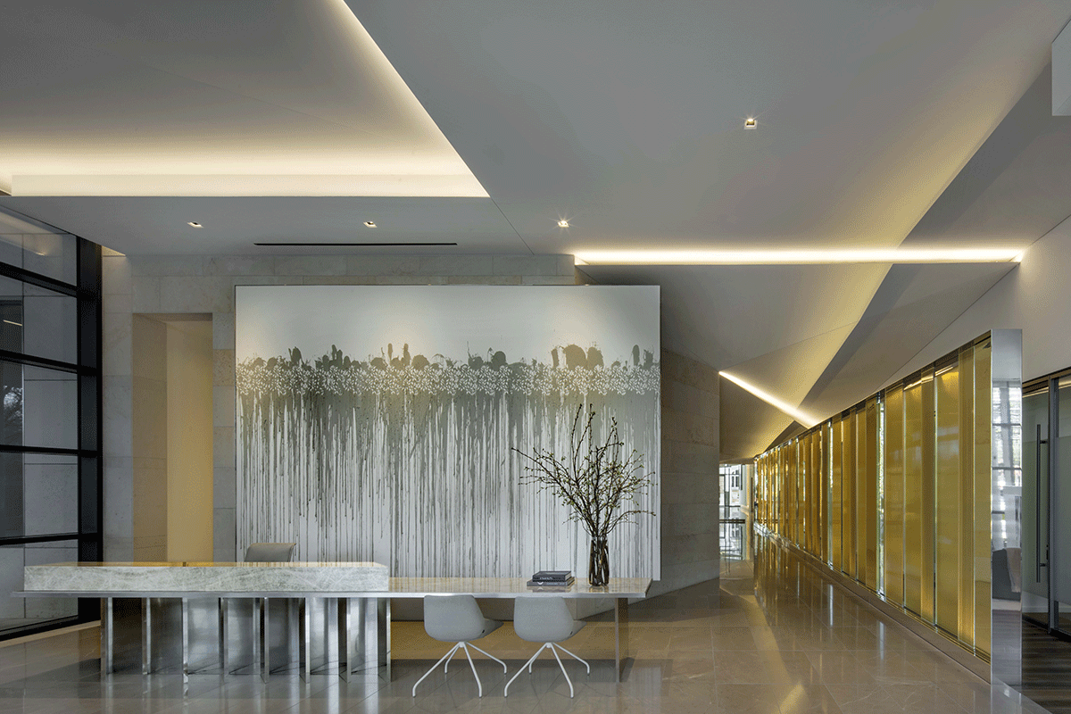 A lobby with a table and chairs and a large painting on the wall.