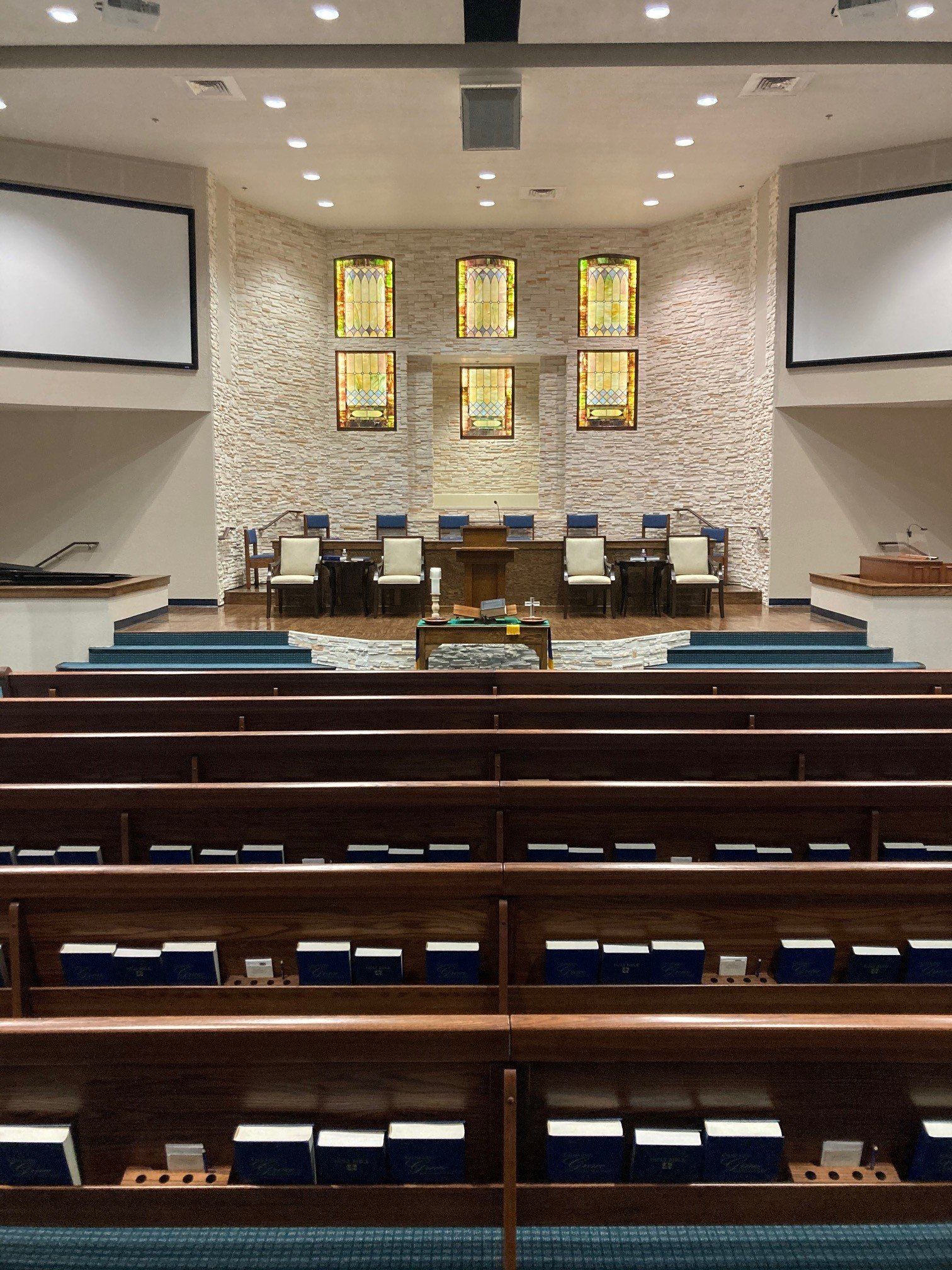 The inside of a church with rows of wooden benches and stained glass windows