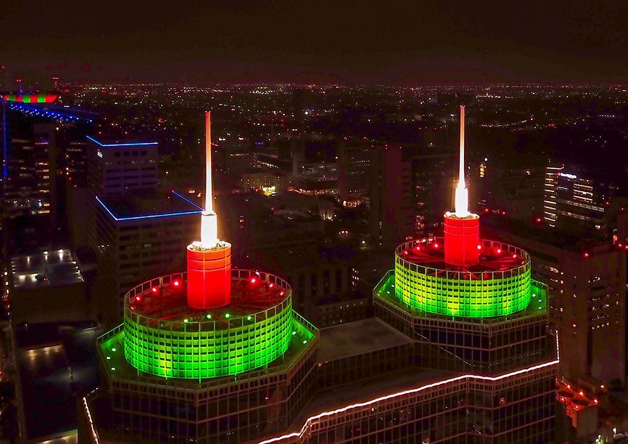 Two candles are lit up on top of a building at night.