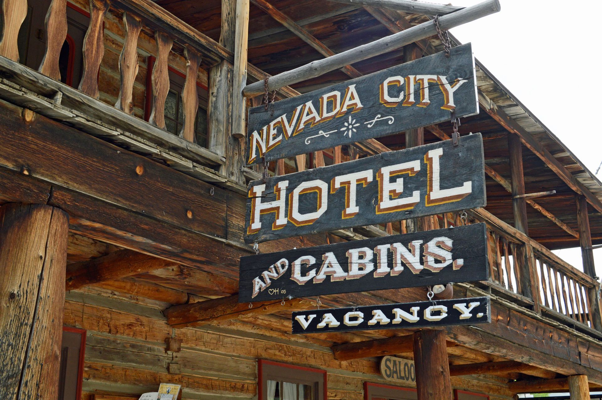 Weathered wooden sign for Nevada City Hotel and Cabins on a rustic building exterior.
